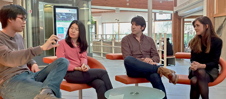 A student talking and gesturing using his hands while colleagues look on intently 