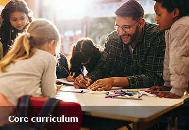 A teacher sits surrounded by happy looking pupils doing a shared task