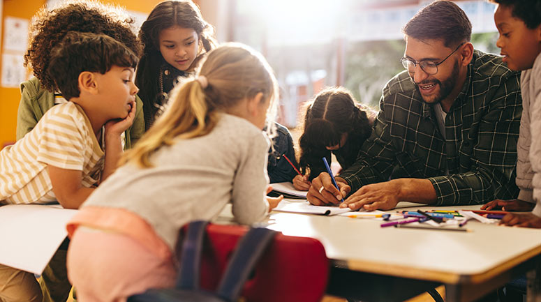 A teacher suurounded by happy learners doing a shared task