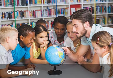 Primary school children looking intently as a teacher shows them something on a globe