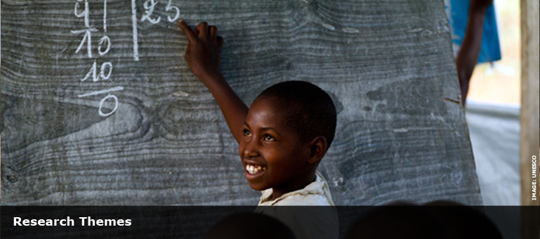 child at chalk board with sums on smiling