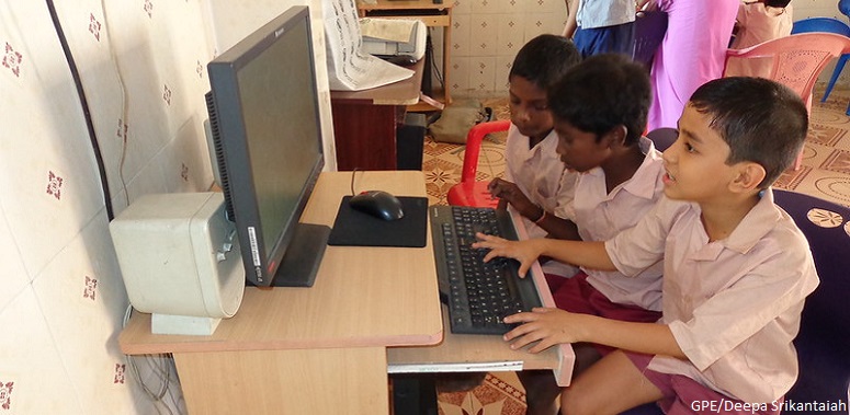 Three students on the computer in primary school in Tamil Nadu India